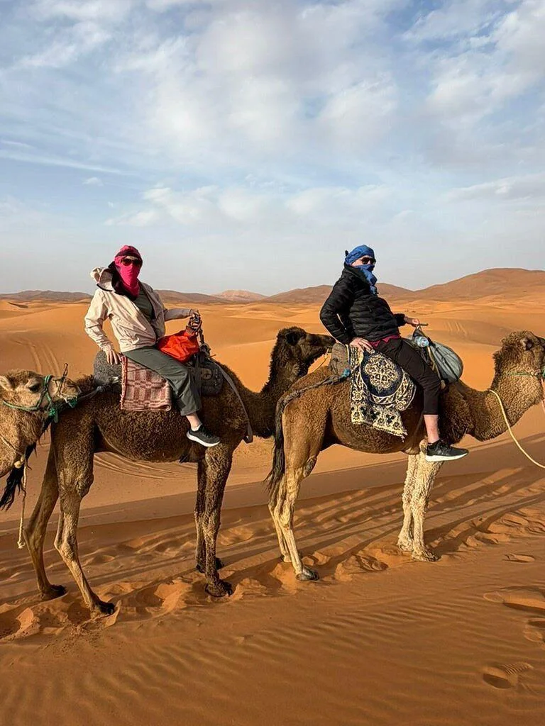 Travellers riding camels across the dunes near Merzouga
